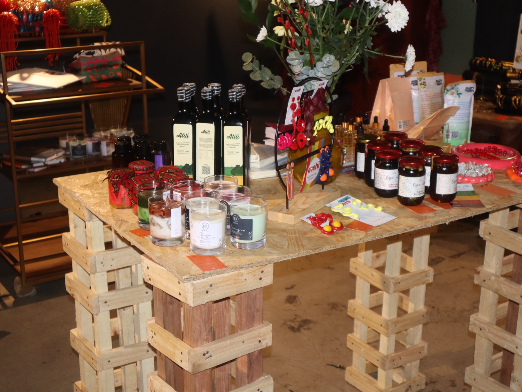 Styled pop-up table with candles, oils and preserves under fresh flowers